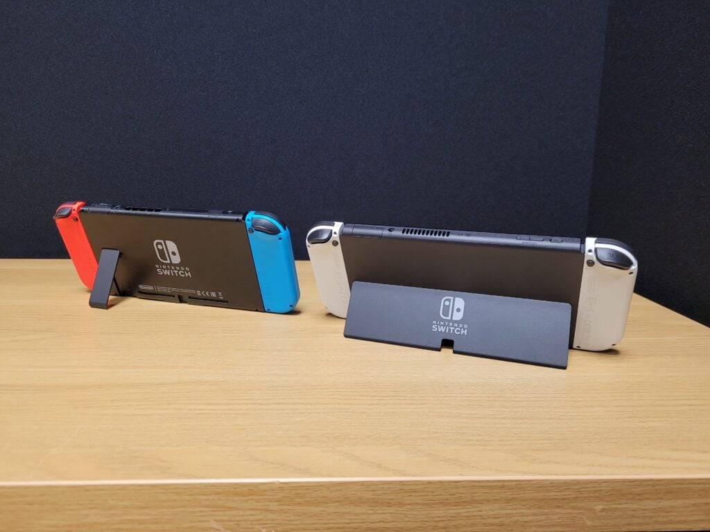 Nintendo Switch OLED sitting by standard Switch, with their stands on display