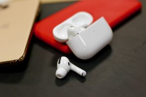 AirPods Pro earbud kept beside it's case with one earbud mkept inside th case on a black table
